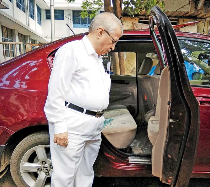 Manohar Kandalkar inspects his car. He was sitting on the left side in the rear seat and had a lucky escape