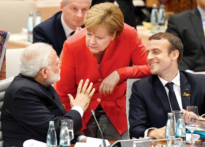 Prime Minister Narendra Modi, German Chancellor Angela Merkel and French President Emmanuel Macron talk ahead of a working session on the first day of the G20 summit in Hamburg yesterday. Pic/AFP