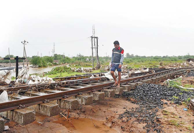 A man walks on railway tracks damaged due to heavy rains, near Maliya Miyana station near Ahmedabad. Pic/AFP