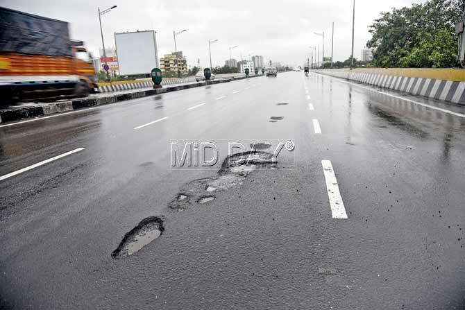 Commuters were seen negotiating huge potholes at JVLR and the Western Express Highway stretch near Santacruz this morning. Pics/ Pradeep Dhivar