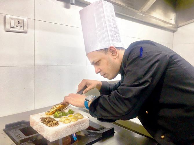 Chef Rohit Lobo sears salmon and vegetables on the Himalayan pink salt block