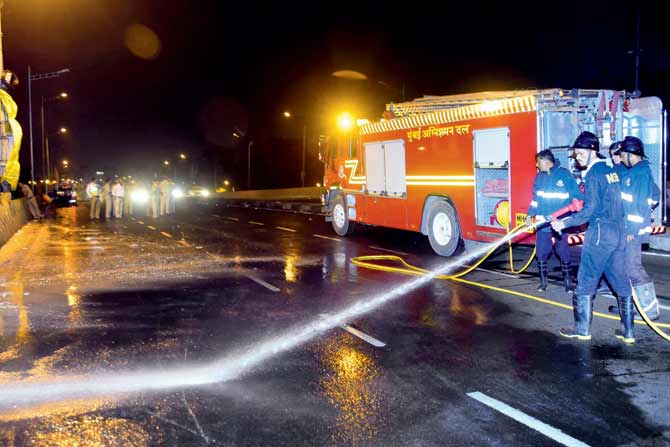 Firemen clean the highway in the early hours of Monday