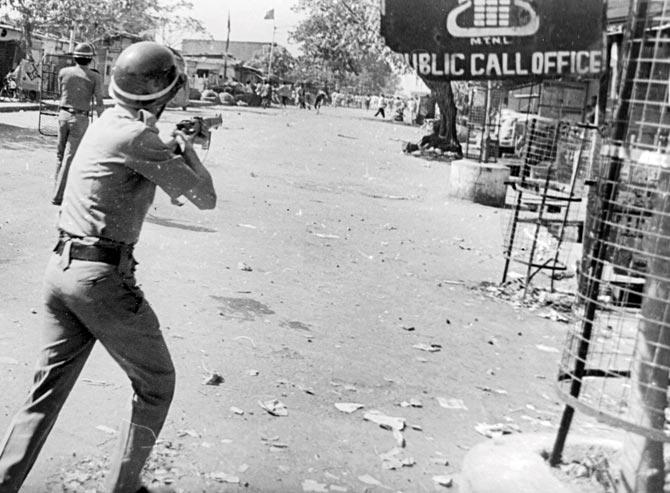 A policeman takes aim at a group of protesters in Ramabai Nagar, Ghatkopar, in 1997. Ten people were killed when a team of State Reserve Police personnel opened fire on residents who were protesting the desecration of an Ambedkar statue. It was also the time religious and regional identities became important in a city that afforded anonymity. File photo