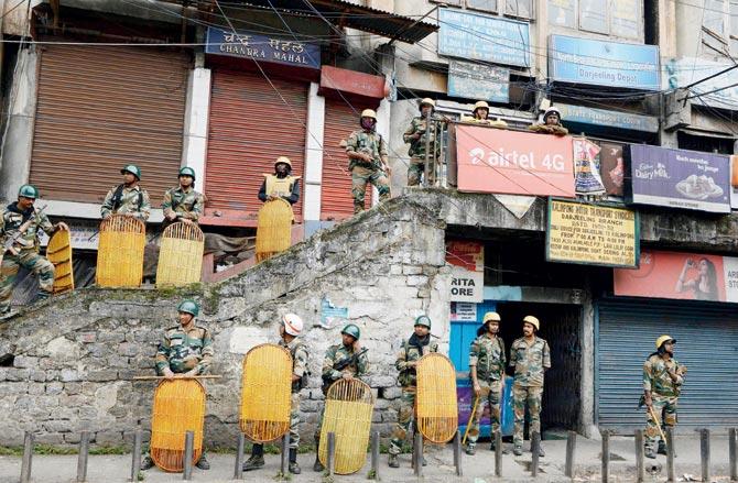 Policemen stand guard outside shuttered stores in Darjeeling on Sunday. Pic/AFP