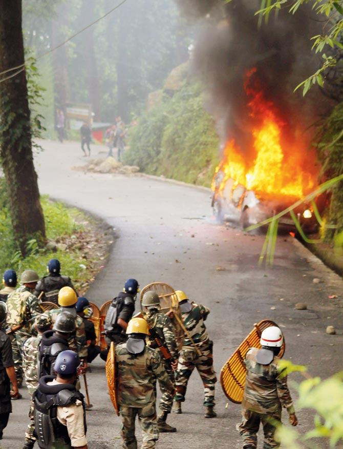 Security forces take cover during clashes with Gorkha Janmukti Morcha (GJM) supporters yesterday. PIC/AFP