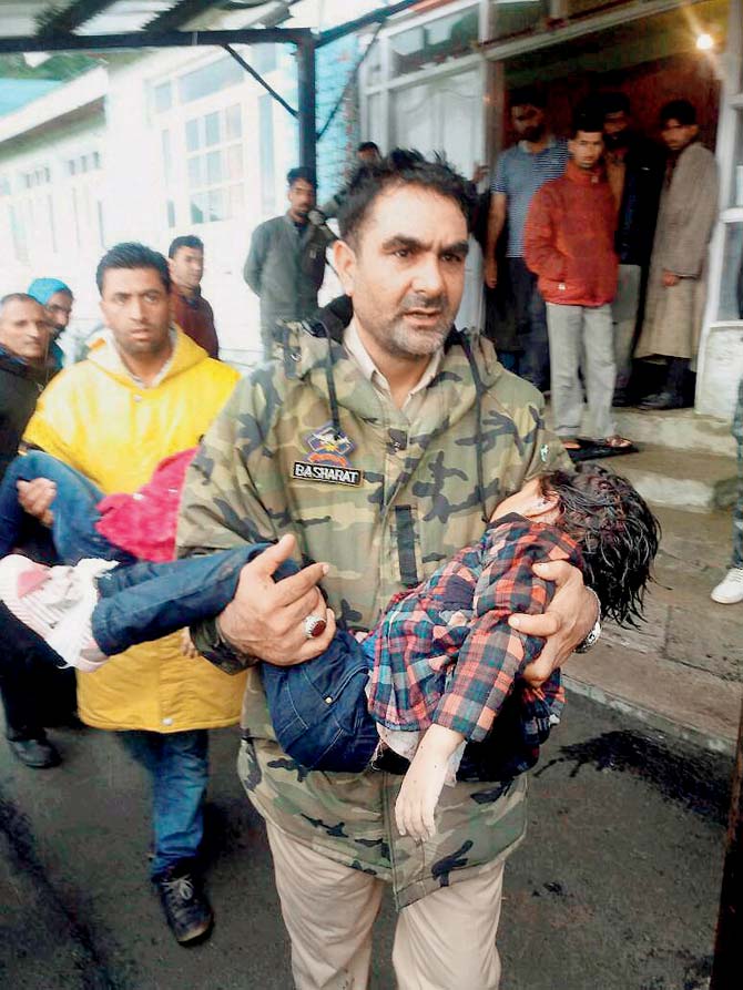 A policeman carries an injured child to a hospital. Pic/PTI