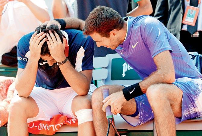 Injured Nicolas Almagro (left) is comforted by Juan Martin del Potro during the French Open third round at Paris yesterday. Pic/AFP
