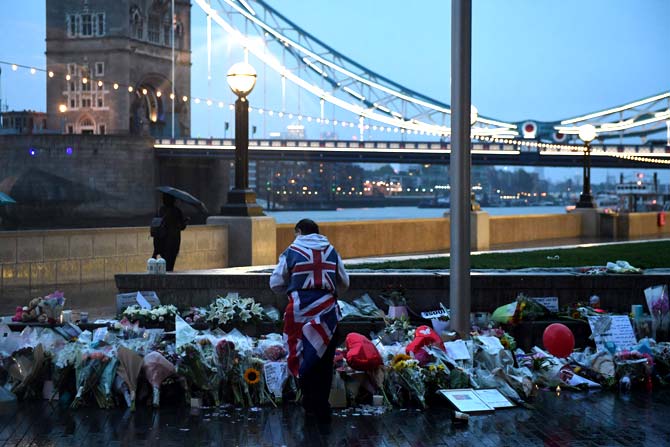A man stands near flowers layed at Potters Fields Park in London on June 5, 2017, after a vigil to commemorate the victims of the terror attack on London Bridge. Pic/AFP