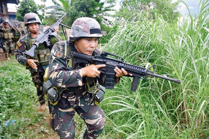 Philippine troops patrol a grassy area near the frontline in Marawi on Mindanao. file Pic/AFP