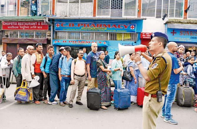 A policeman uses a megaphone to organise queues of tourists waiting to leave Darjeeling. Pic/AFP