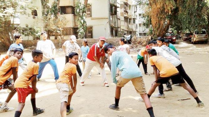 Sharad Dhage (red jersey) coaching youngsters during a summer camp at Kumud Nagar ground in Goregaon (West) recently  