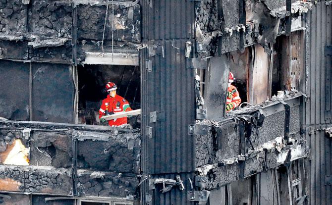 Members of the emergency services work on the middle floors of the charred remains of the Grenfell Tower. Pic/AFP