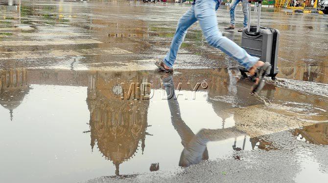 A commuter jumps over a puddle near Chhatrapati Shivaji Terminus, as areas across the city reported waterlogging following heavy rains yesterday. Pic/Suresh Karkera