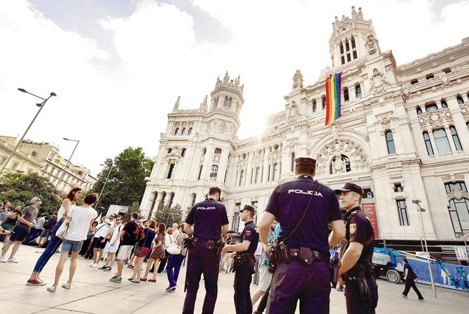 Spanish policemen guard the setting up of the gay pride flag, on the facade of the Cibeles Palace, the Madrid City Hall. Three million revellers are expected as Madrid hosts WorldPride 2017