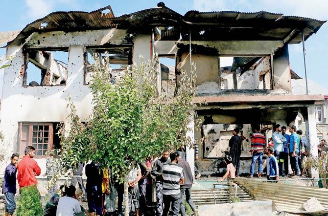 Locals look at the house at Kakapora where the terrorists were hiding, after the encounter. Pic/AFP