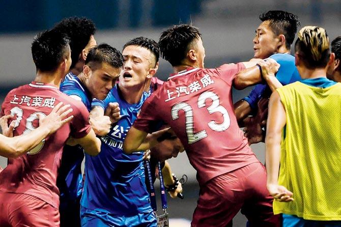 Players from Shanghai SIPG (in red) and Guangzhou R&F exchange blows during a Chinese Super League match yesterday. Pic/AFP