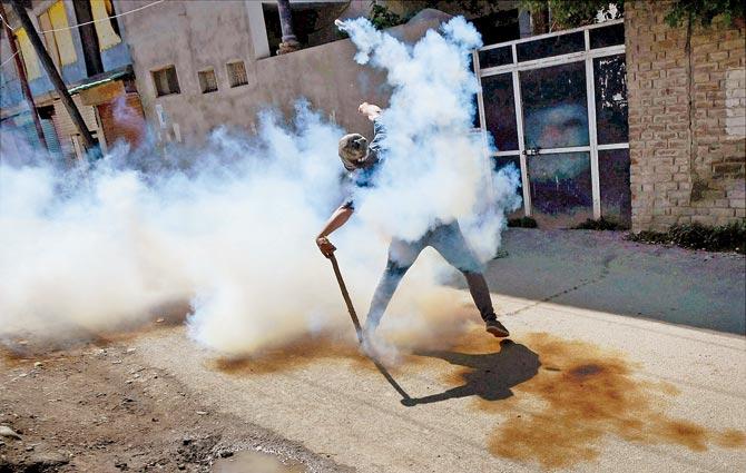 A file picture of a protester throwing a teargas shell back at the police during a clash in Srinagar.