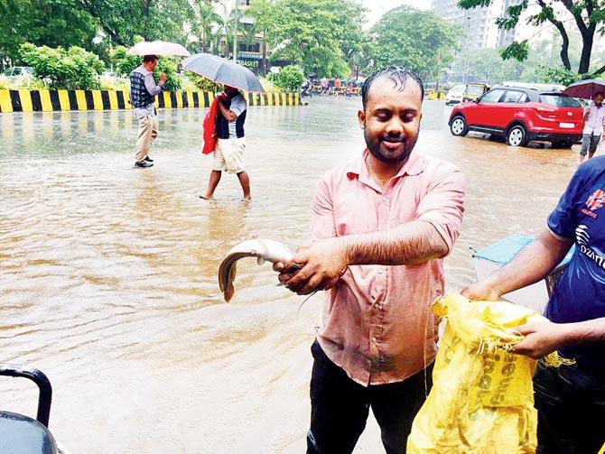 A fisherman gets lucky as he finds a fish at the waterlogged  120 Feet Road in Kandivli yesterday.  Pic courtesy/Tejas Mehta