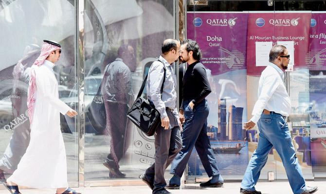 People walking past the Qatar Airways branch in the Saudi capital Riyadh, after it had suspended all flights to Saudi Arabia following a severing of relations between major gulf states and gas-rich Qatar.