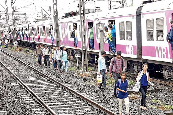 Commuters seen walking on the railway tracks near Virar station early this morning after a point failure on platform 8