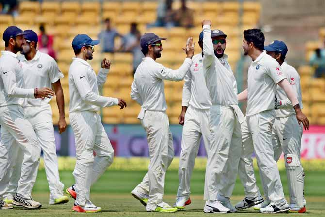 Indian players celebrate after Umesh Yadav took the wicket of Steve Smith during the fourth day of the second test against Australia at Chinnaswamy stadium, Bengaluru. Pic/ PTI