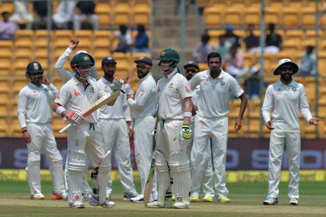 Australian captain Steve Smith, (C), vice captain David Warner (2L) and the Indian team wait for the third umpire