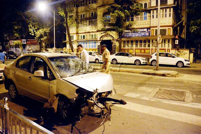 A police official is seen examining the condition of the car that rammed into an electric pole on Peddar Road flyover last night. Pic/ Sneha Kharabe