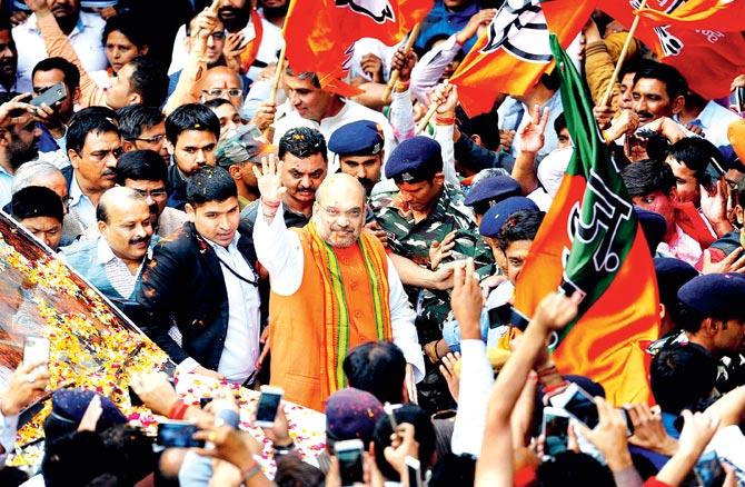 BJP president Amit Shah waves at party workers on his arrival at the party headquarters in New Delhi. Pics/PTI and AFP
