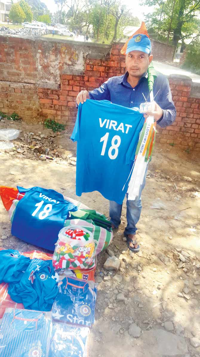 A vendor holds up a Virat shirt outside the HPCA Stadium on Saturday. Pic/Ashwin Ferro