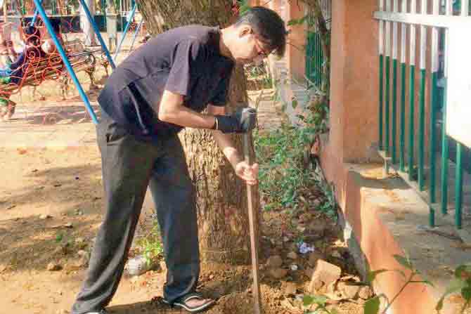 A resident digs a spot to plant an adopted tree