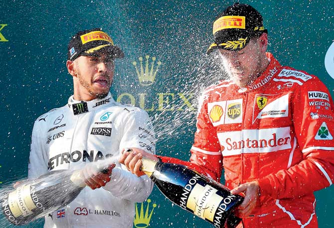 Mercedes’ Lewis Hamilton (left) sprays champagne on Ferrari’s Sebastian Vettel after the Australian GP in Melbourne yesterday. Pic/AFP