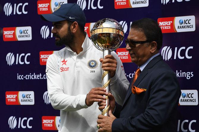 India captain Virat Kohli receives the ICC test team trophy from Sunil Gavaskar. Pic/ AFP