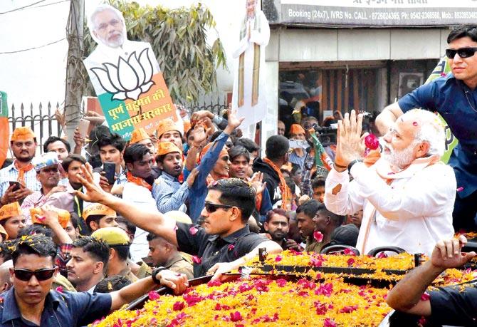 PM Modi greets the crowd during the roadshow in Varanasi. Pic/PTI