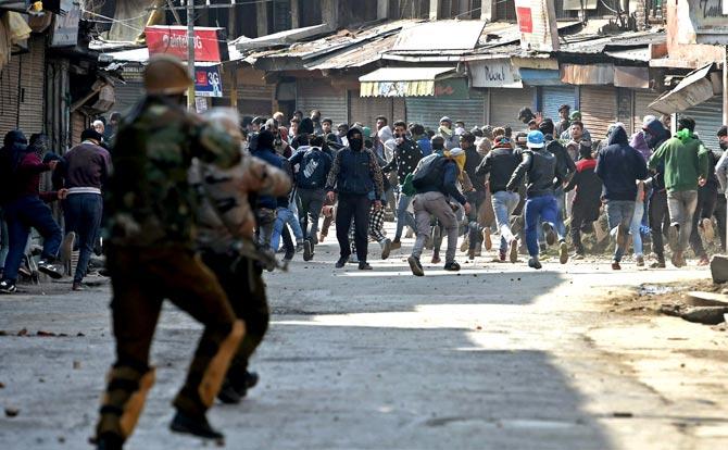Police and CRPF chasing away protesters throwing stones on them during a clash in Srinagar. Pic/PTI