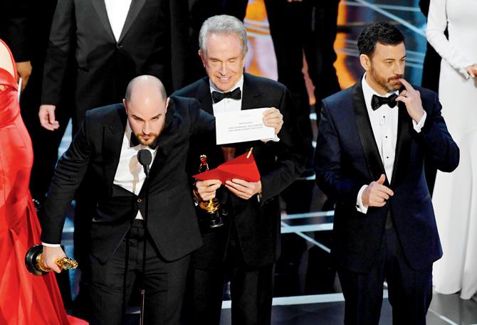 Jordan Horowitz (left) holds up the cue card revealing the real winner; (right) Jimmy Kimmel