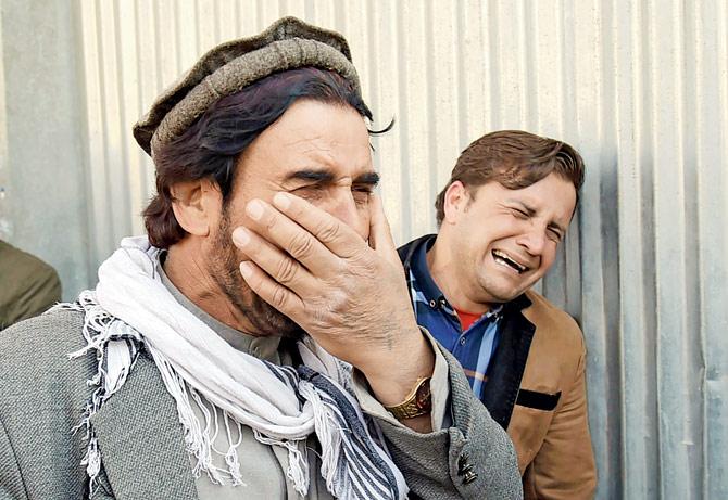 Two Afghan men weep for their relatives in front of the main gate of a military hospital in Kabul. Pics/AFP