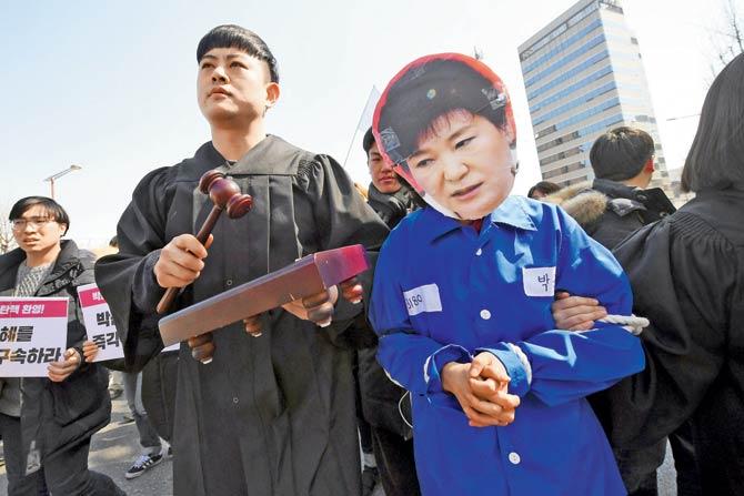 An anti-government activist (right) wearing a mask of South Korea’s President Park Geun-Hye marches toward the presidential Blue House after the announcement of the Constitutional Court’s decision. Pic/AFP