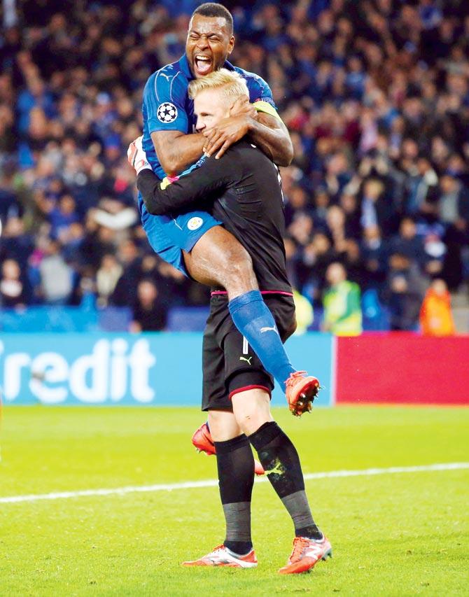 Leicester keeper Kasper Schmeichel (right) celebrates after saving a penalty with Wes Morgan during the Champions League Round-of-16 encounter at the King Power Stadium on Tuesday