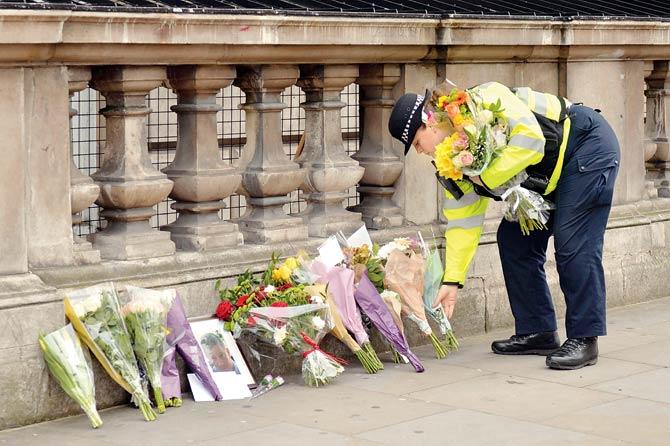 A police officer lays flowers on Whitehall