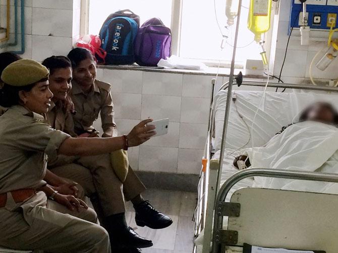 Woman constables posted for the security of gang rape and acid attack survivor, taking selfies in KGMU on Friday. The Uttar Pradesh police has ordered action against the three "insensitive" woman constables after their selfies. PTI 