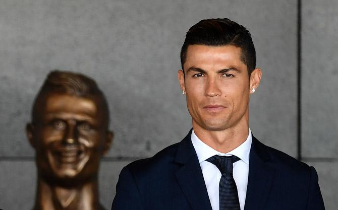Cristiano Ronaldo stands past a bust presented during a ceremony where Madeira
