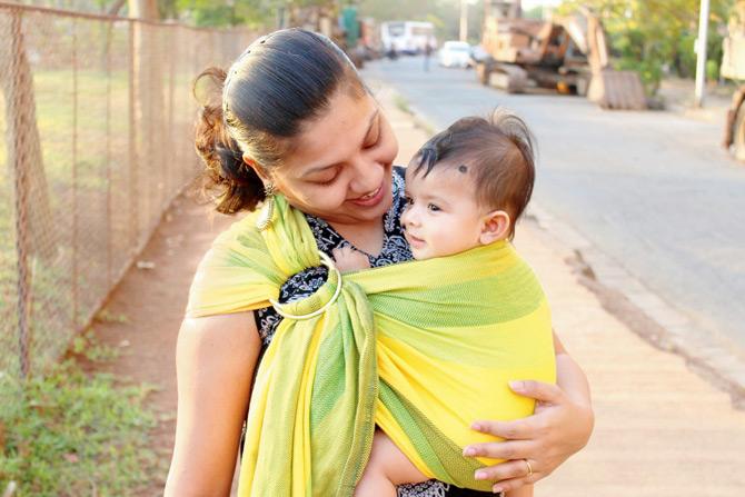 Nikita A wears her eight-month-old daughter in a cloth sling