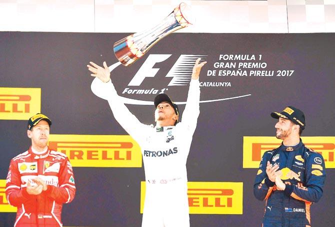 British racer Lewis Hamilton centre celebrates with the trophy after winning the Spanish Grand Prix as Ferrari driver Sebastien Vettel left and Red Bull driver Daniel Ricciardo applaud at the Circuit de Catalunya in Montmelo on the outskirts of Barcelona yesterday. Pic/AFP