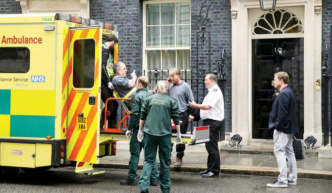 A worker is helped from 10 Downing Street into an NHS ambulance after the cyber strike, which hit dozens of British hospitals. Pic/AFP