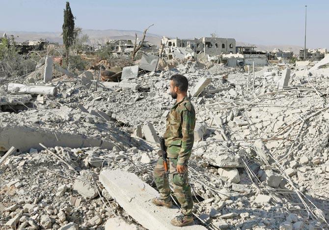 A member of the Syrian pro-government forces stands on rubble near Damascus. Pic/AFP