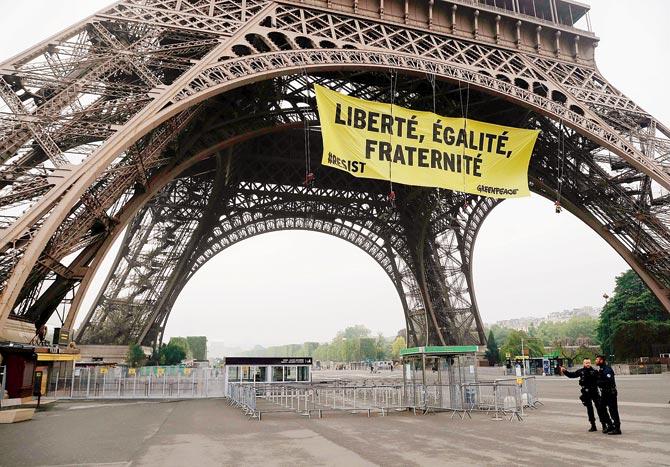 Police officers stand by after Greenpeace activists unveiled a banner on the Eiffel Tower. Pics/AFP