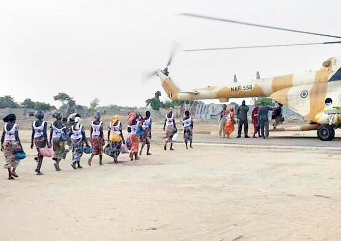 At a military base in Borno State, some of the 82 rescued Chibok girls head towards a Nigerian Army helicopter. Pic/AFP