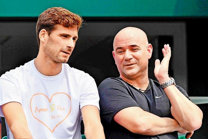 Coach Andre Agassi (right) and Marko Djokovic, the brother of Novak, watch the first round action from the sidelines yesterday. Pic/AFP