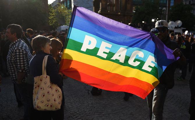 People hold a "peace" flag during a vigil in Albert Square in Manchester, northwest England, in solidarity with those killed an injured in the May 22 terror attack at the Ariana Grande concert at the Manchester Arena. AFP PHOTO / Oli SCARFF