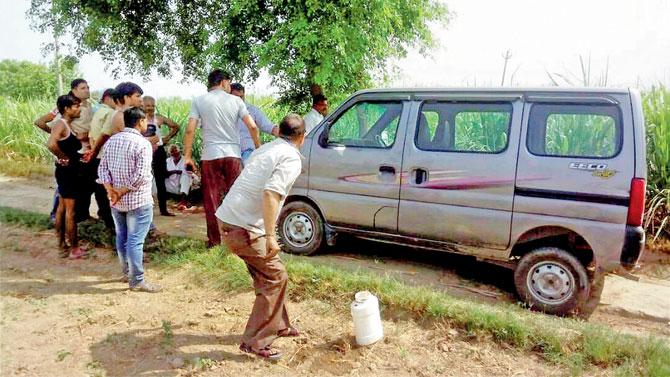 People look at the vehicle which was targetted as police inspect it. Pic/PTI